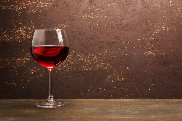 木製の壁の背景に木製のテーブルの赤ワインのガラス - 写真・画像