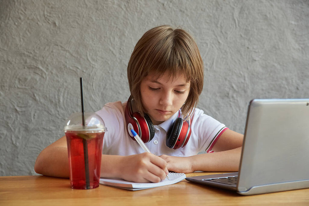 Klein blank meisje aan tafel, studeert met latop. online onderwijs - Foto, afbeelding