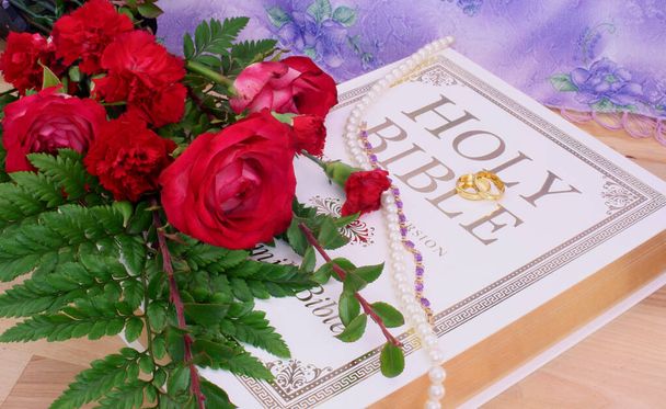 Róże z Biblią i obrączki ślubne na drewnianym stole - Zdjęcie, obraz