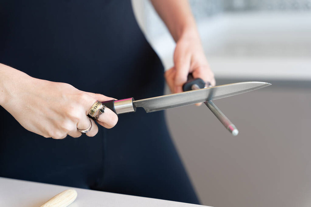 nő élező egy kést egy daráló, közelkép kilátás elmosódott vízszintes háttér - Fotó, kép