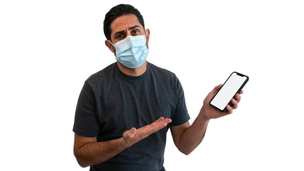 白人男性が白い背景スタジオに隔離された滅菌顔マスクを持つスマートフォンに手を指しています。検疫パンデミックコロナウイルスウイルスの概念で携帯電話のデバイスを示す驚くべき男. - 写真・画像