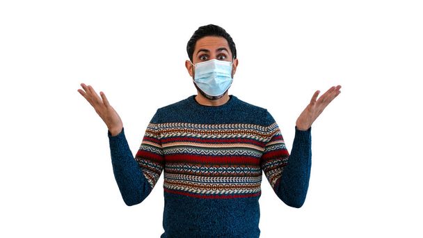 Überraschte Mann zeigt mit zwei Händen nach oben, während mit Mundschutz sicher vor Coronavirus isoliert auf weißem Hintergrund. Konzept der Covid-19-Pandemie-Quarantäne - Foto, Bild