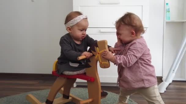 Two girls sisters fighting for a wooden rocking horse - Footage, Video