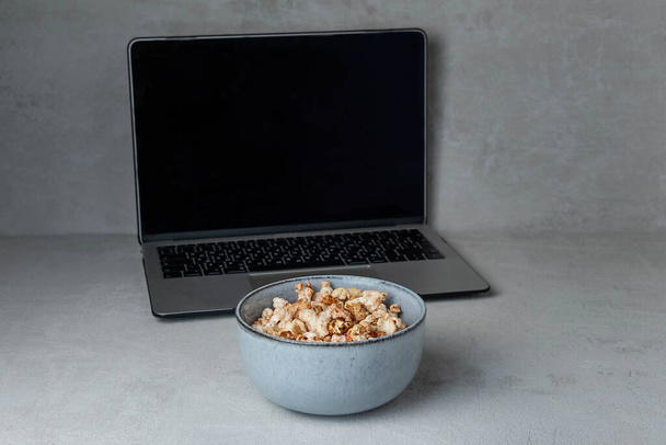 ceramic bowl with popcorn on the background of a laptop , the concept of remote work ,freelance - Foto, immagini