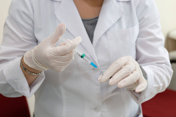 Woman doctor with syringe preparing vaccine. Doctor's hands in white gloves with syringe close-up. COVID-19 coronavirus vaccination concept. Pharmacy drugs and therapy. - Фото, изображение