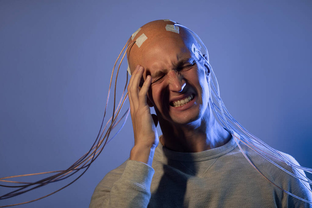 A young man with his head entangled in wires, screaming clutching his head, - Foto, immagini