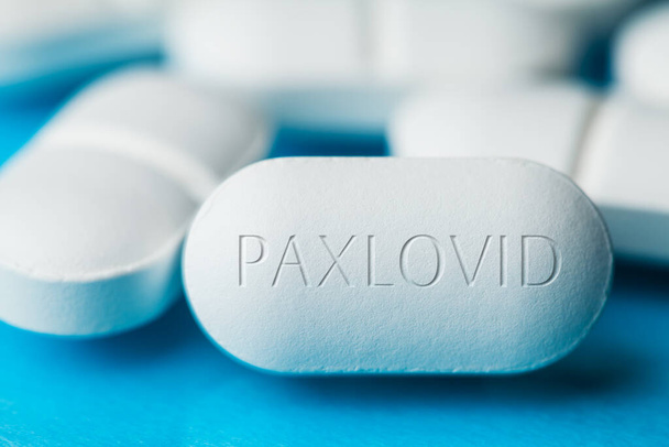 COVID-19 médicament antiviral expérimental PAXLOVID, pile de pilules blanches avec des lettres gravées sur le côté, potentiel expérimental OMS Coronavirus cure, crise épidémique pandémique, isolé sur fond bleu - Photo, image