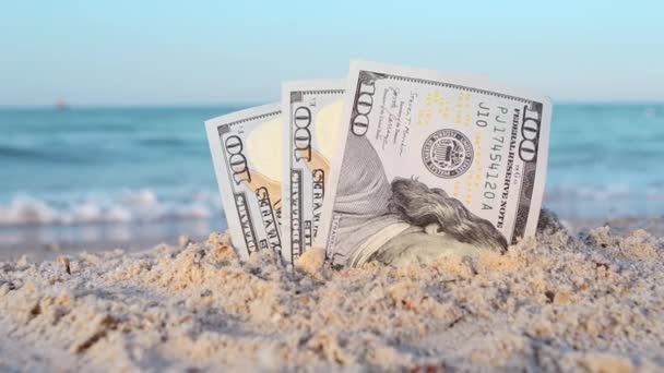 Két egydolláros bankjegy, félhomokba temetve a homokos tengerparton, közeli felvételeken.. - Felvétel, videó
