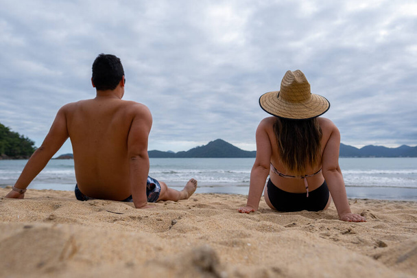 latin couple on the beach on a cloudy day looking at the sea, vacation in brazil ubatuba back view - Fotó, kép