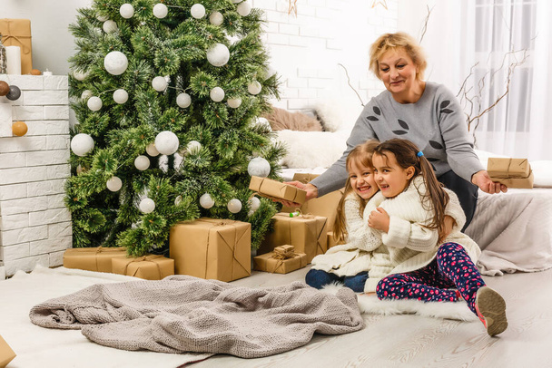 zwei Mädchen vor dem Weihnachtsbaum mit Geschenken und Kamin - Foto, Bild