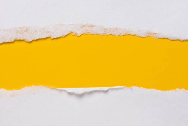 Torn sheet of white paper on a yellow background with a place for an inscription. Copy space. Top view.  - Фото, зображення