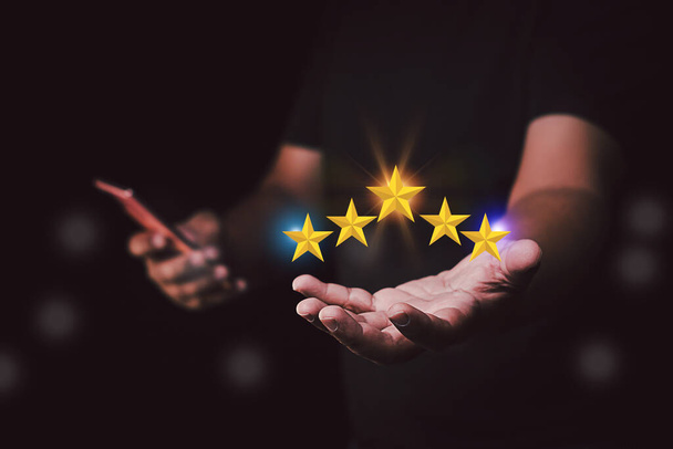 Koncepcja zadowolenia klienta. Ręka trzymająca gwiazdy do pięciu gwiazd. daje pięciogwiazdkową ocenę. Ocena usług, ocena pozytywna dla klienta - Zdjęcie, obraz