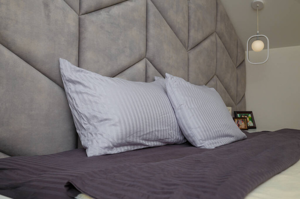 Серая спальня, кровать, подушки, мягкая подушка. Современный дизайн интерьера, крупный план - Фото, изображение