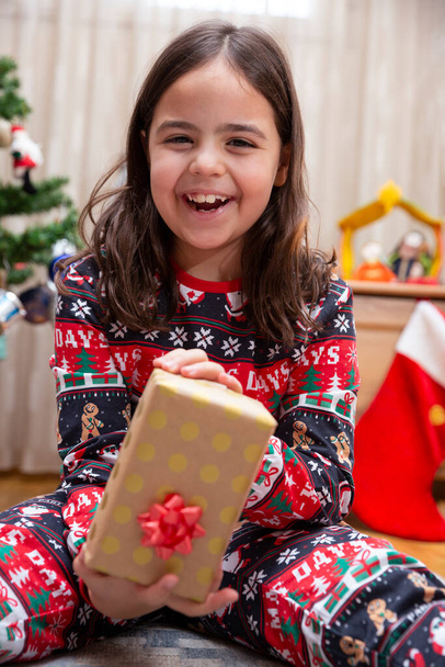 Portrait of very happy little Caucasian girl showing her Christmas gift. - Foto, Imagen
