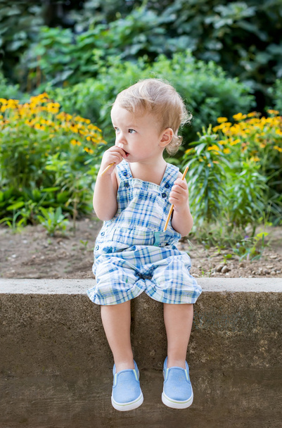 lindo niño comiendo dulce paja sentado
  - Foto, Imagen