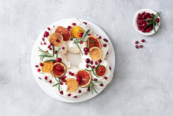 Meringues pavlova cake wreath with whipped  cream, pomegranate and orange - Photo, Image