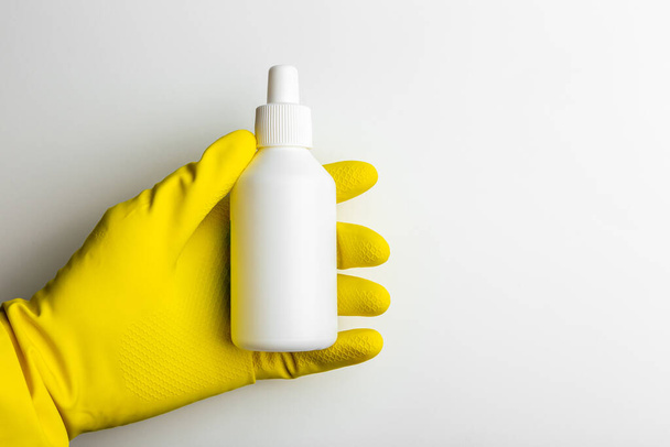 ένα χέρι σε ένα λαστιχένιο γάντι κρατά ένα λευκό λευκό δοχείο - Φωτογραφία, εικόνα
