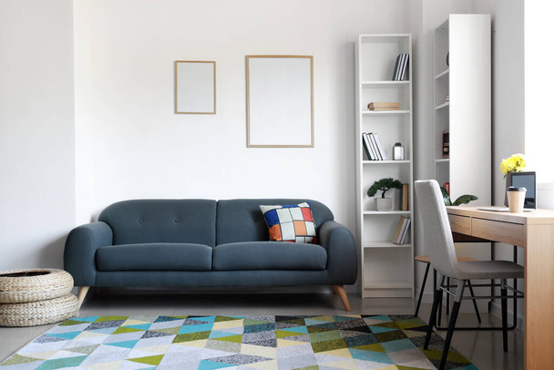 Carteles en blanco en la pared clara y sofá en la sala de estar - Foto, Imagen