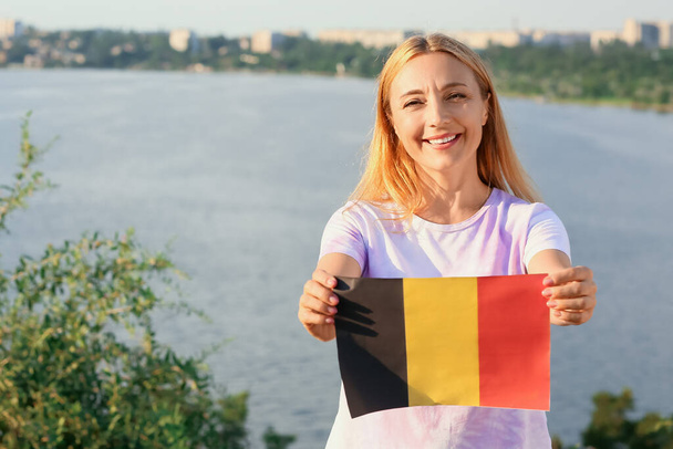 Dojrzała kobieta z flagą Belgii w pobliżu rzeki - Zdjęcie, obraz