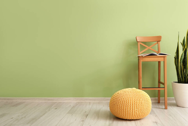 Stuhl, Hocker und Zimmerpflanze in der Nähe der Farbwand - Foto, Bild