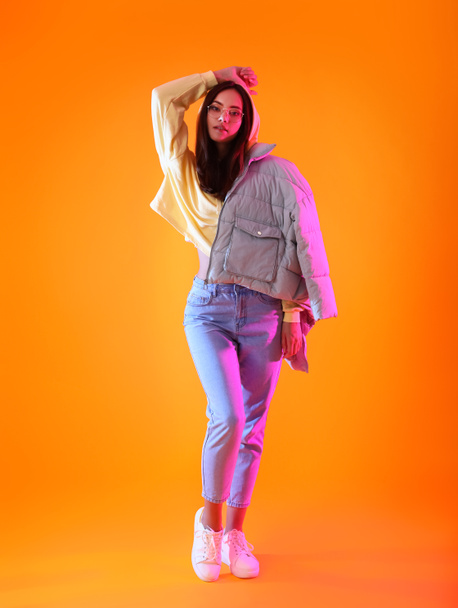 Pretty young woman in warm clothes on color background - 写真・画像