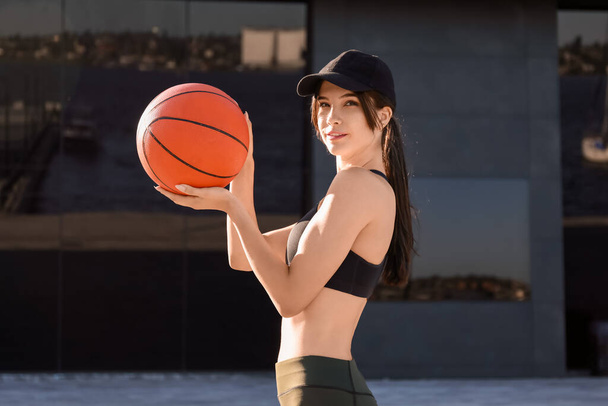 Giovane donna sportiva con cappuccio e palla all'aperto - Foto, immagini
