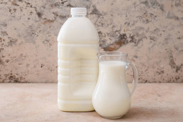 Gallon bottle and jug of milk on table - Foto, Imagen