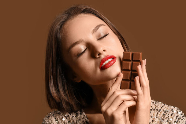 Schöne Frau mit süßer Schokolade auf farbigem Hintergrund - Foto, Bild
