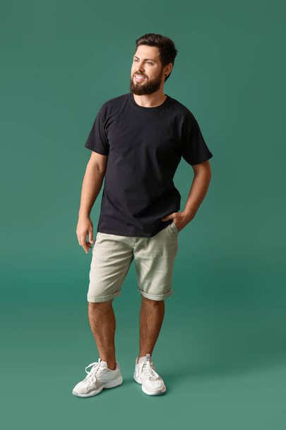 Knappe man in zwart t-shirt op groene achtergrond - Foto, afbeelding