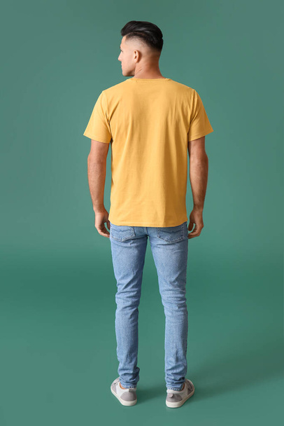 Handsome young man in stylish t-shirt on color background, back view - Fotó, kép
