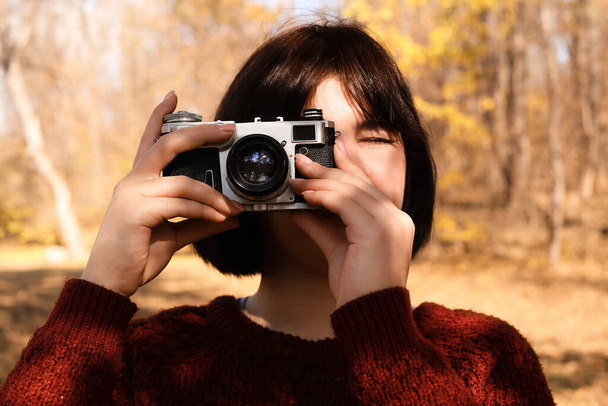 Νεαρή γυναίκα τραβάει φωτογραφίες στο πάρκο του φθινοπώρου - Φωτογραφία, εικόνα