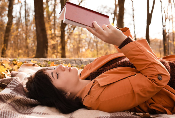 Junge Frau auf kariertem Lesebuch im Herbstpark - Foto, Bild