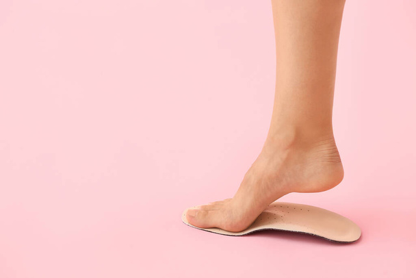 Naisen jalka ja ortopedinen pohja vaaleanpunaisella taustalla - Valokuva, kuva