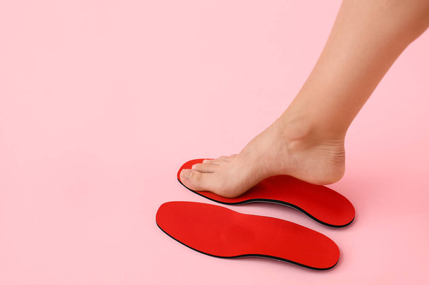 Naisten jalka ja punainen ortopedinen pohjalliset vaaleanpunainen tausta - Valokuva, kuva