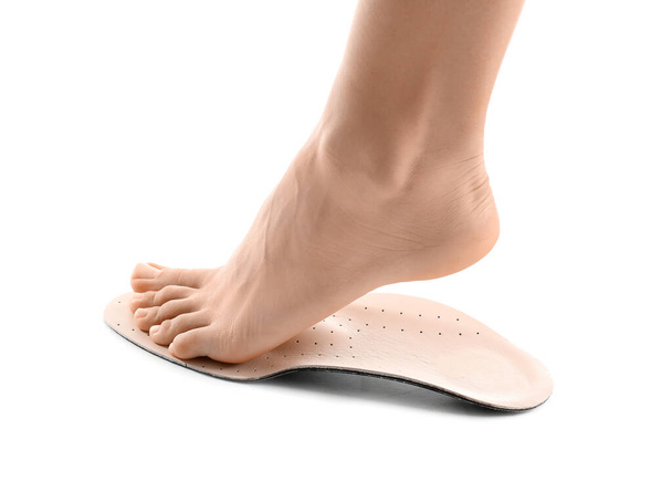 Weiblicher Fuß und orthopädische Einlegesohle auf weißem Hintergrund - Foto, Bild