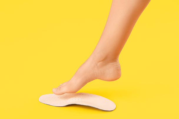 Female foot and orthopedic insole on yellow background - Zdjęcie, obraz