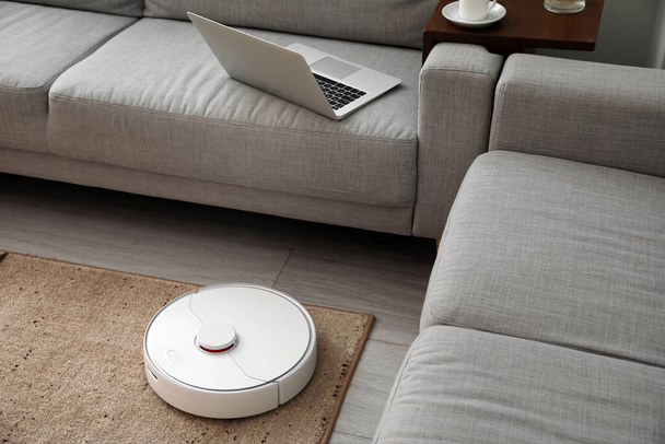 Modern robot vacuum cleaner on soft carpet in room - Photo, Image