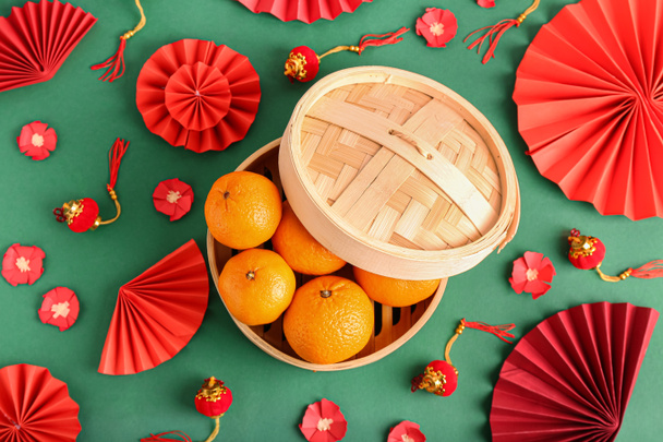 Schachtel mit schmackhaften Mandarinen und chinesischen Symbolen auf farbigem Hintergrund - Foto, Bild