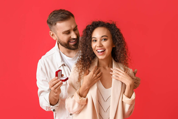 Young man proposing to his girlfriend on color background - Photo, Image