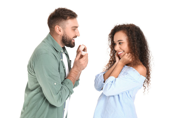Young man proposing to his girlfriend on white background - Photo, image
