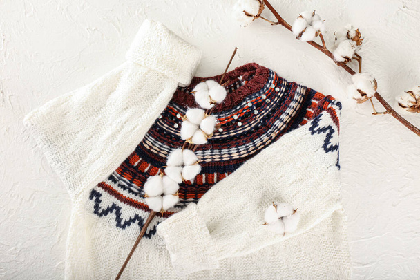 Warm sweater with stylish pattern and cotton flowers on light background - Zdjęcie, obraz