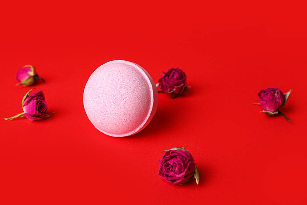 Bath bomb and dried rose flowers on red background - Photo, Image