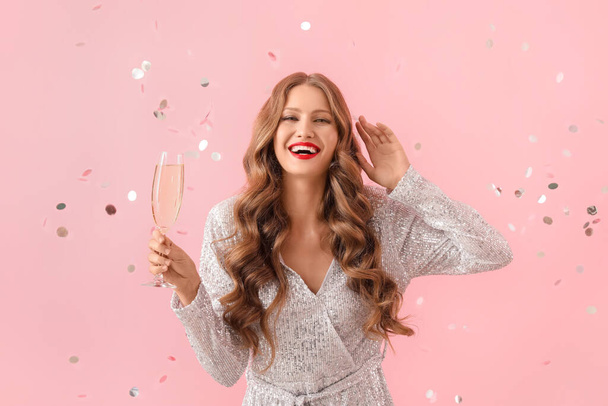 Şampanyası ve renkli arka planda düşen konfetisi olan güzel, mutlu genç bir kadın. - Fotoğraf, Görsel