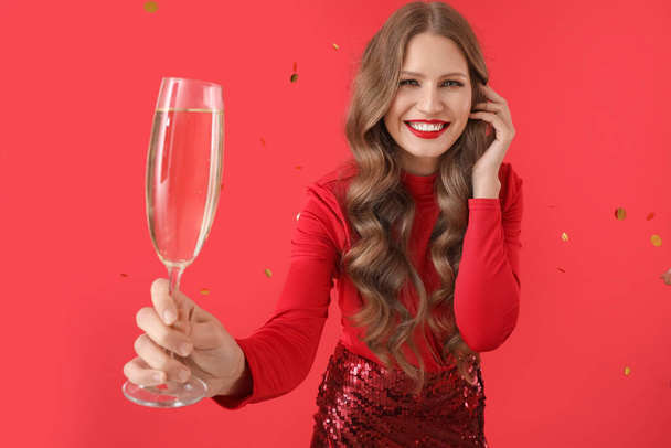 Красивая молодая женщина с шампанским и падающие конфетти на цветном фоне - Фото, изображение