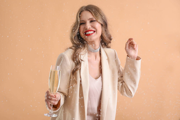 Beautiful young woman with champagne and falling snow on color background - Photo, Image
