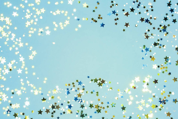 Holiday Festive background. gold and silver star confetti glitter scattered on blue background. - Foto, afbeelding