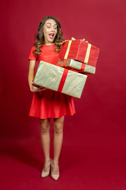 Ενθουσιασμένη γυναίκα με ένα δώρο σε κόκκινο φόντο - Φωτογραφία, εικόνα