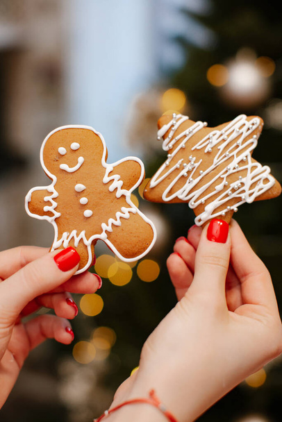 Gingerbread cookies in hands on the background of the New Year tree. Christmas home concept.  - Foto, Imagem