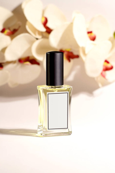 香水のガラス瓶、バックグラウンドで蘭の花、モークアップ  - 写真・画像