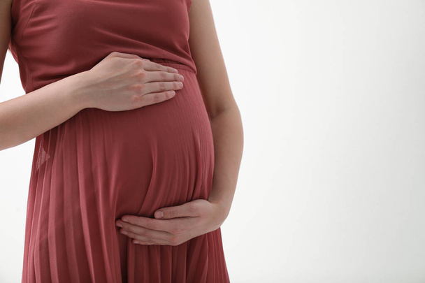 Young pregnant woman on light background, closeup. Space for text - Fotó, kép